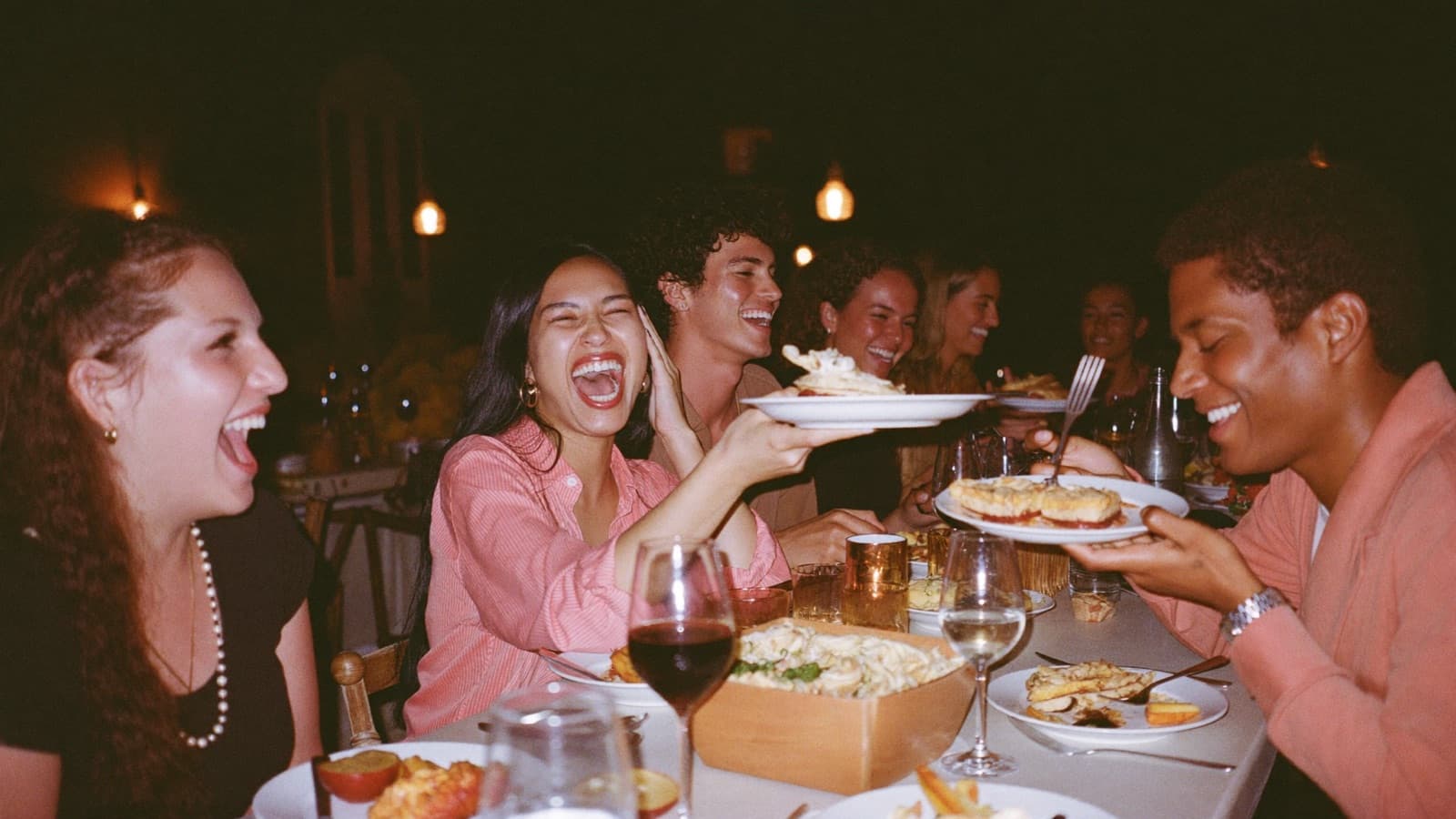 Amigos rindo ao redor de uma mesa de restaurante à noite